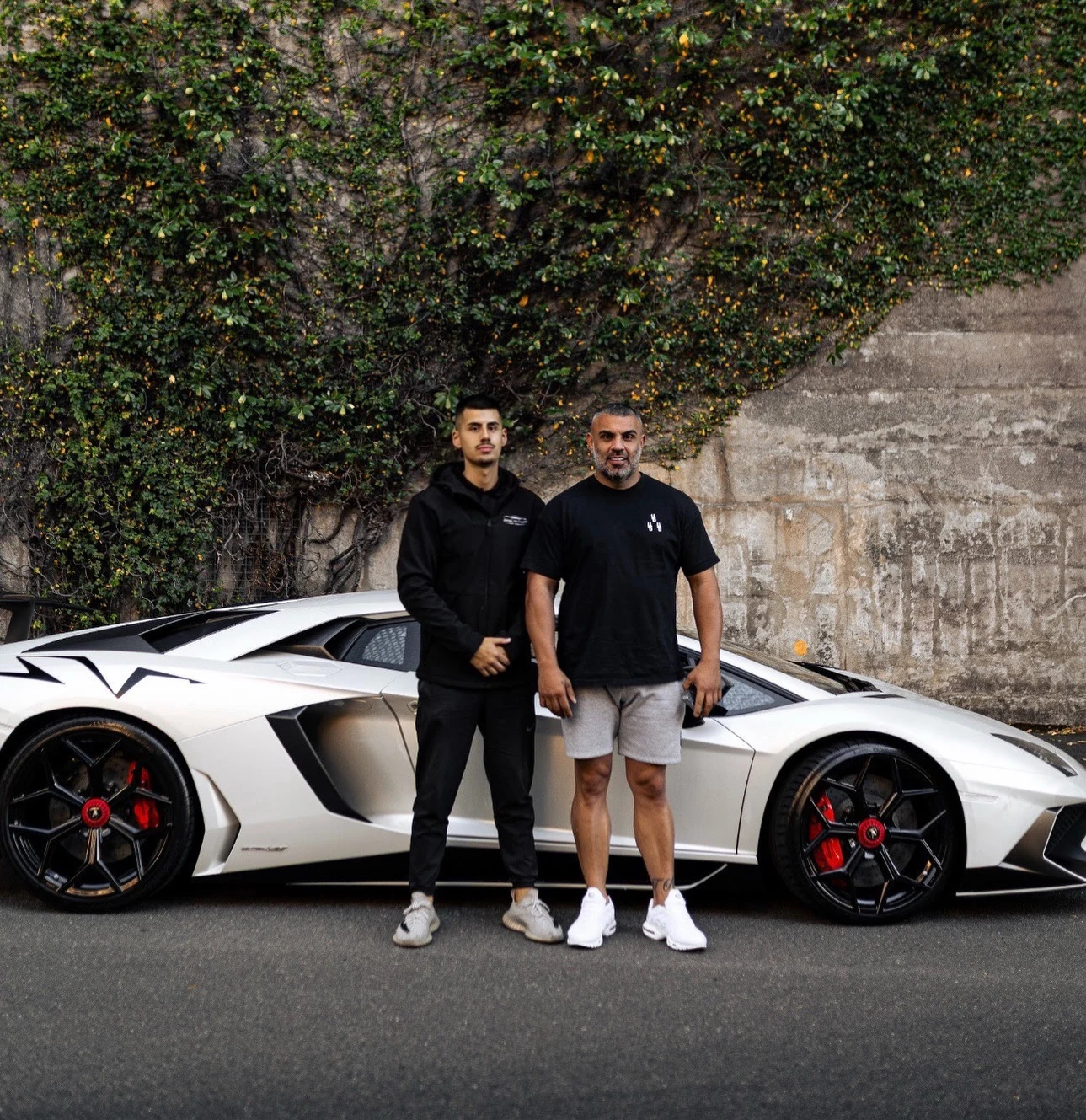 Two people standing in front of a white Lamborghini